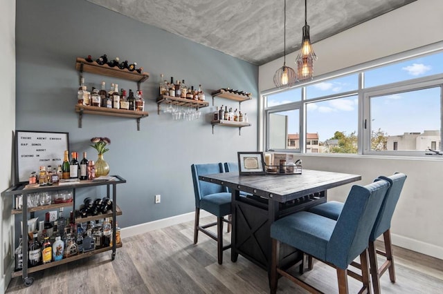 dining area featuring baseboards, a dry bar, and wood finished floors