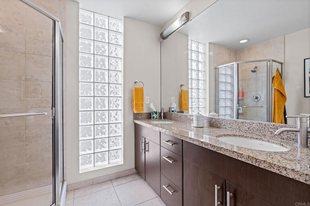 full bathroom with double vanity, tile patterned floors, a stall shower, and a sink