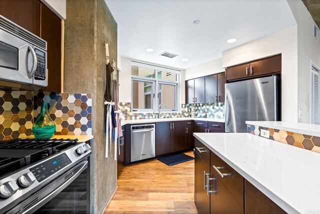 3740 Park Blvd Unit 209, San Diego, CA 92103 - kitchen with stainless steel appliances, decorative backsplash, dark brown cabinets, light wood-style floors, and recessed lighting
