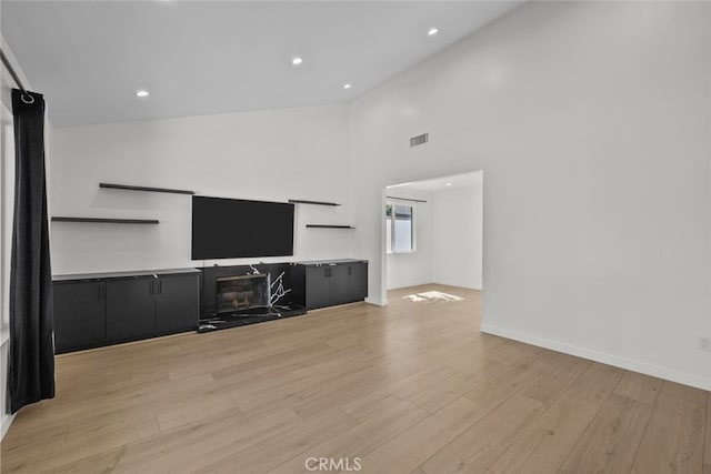 24431 La Glorita Cir, Newhall, CA 91321 - unfurnished living room with high vaulted ceiling, a fireplace, visible vents, baseboards, and light wood-style floors