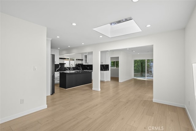 24431 La Glorita Cir, Newhall, CA 91321 - unfurnished living room featuring light wood-style flooring, recessed lighting, and a skylight