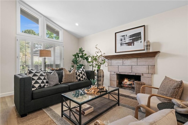 living room featuring recessed lighting, baseboards, a stone fireplace, light wood finished floors, and vaulted ceiling