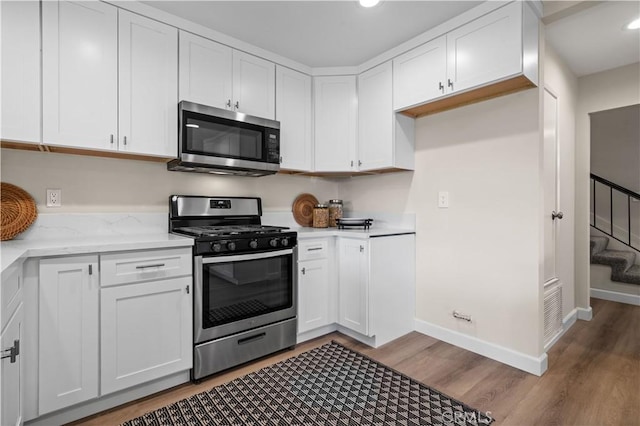 kitchen featuring stainless steel appliances, recessed lighting, light wood-style flooring, white cabinetry, and baseboards