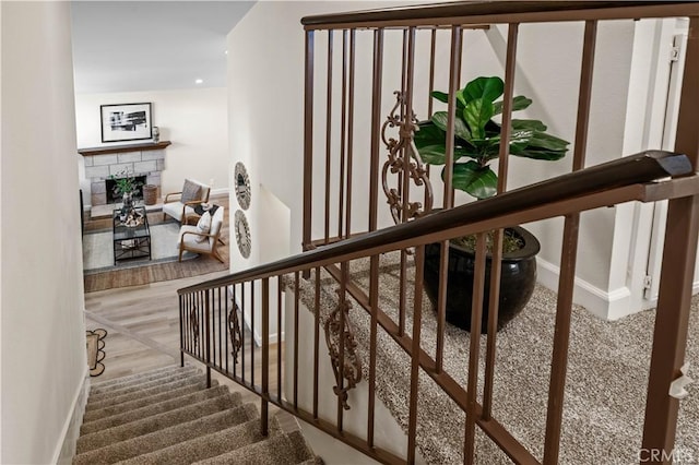 staircase featuring baseboards, a stone fireplace, and recessed lighting