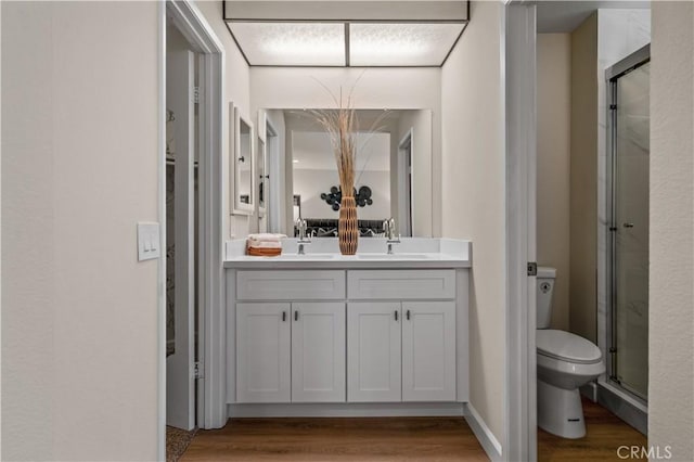 full bath featuring toilet, a shower stall, vanity, and wood finished floors