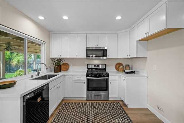 kitchen with white cabinetry, stainless steel appliances, light wood-style flooring, and a sink