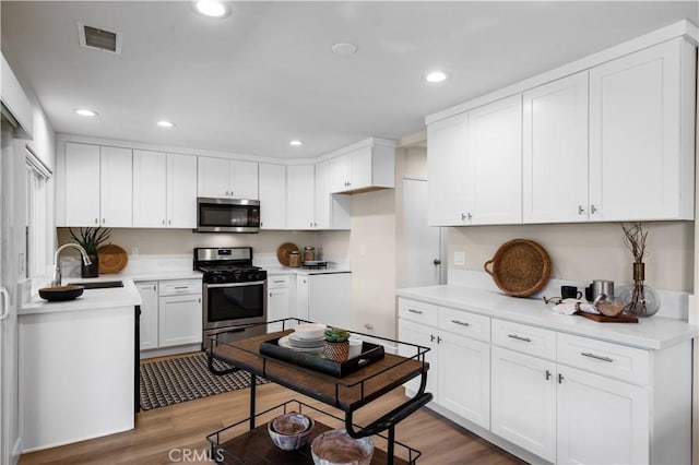 kitchen featuring a sink, stainless steel appliances, white cabinets, visible vents, and recessed lighting