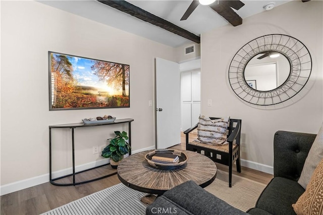 sitting room with wood finished floors, a ceiling fan, visible vents, baseboards, and beamed ceiling