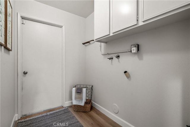 washroom with baseboards, cabinet space, and wood finished floors