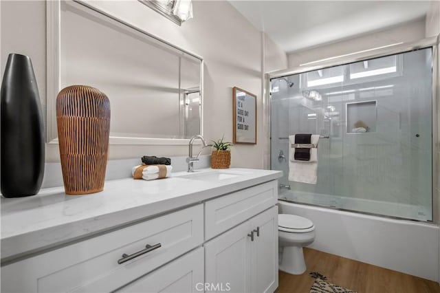 bathroom with toilet, vanity, combined bath / shower with glass door, and wood finished floors