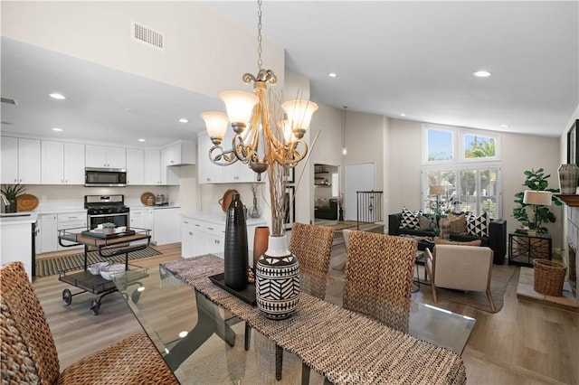dining space with light wood finished floors, a notable chandelier, visible vents, and recessed lighting