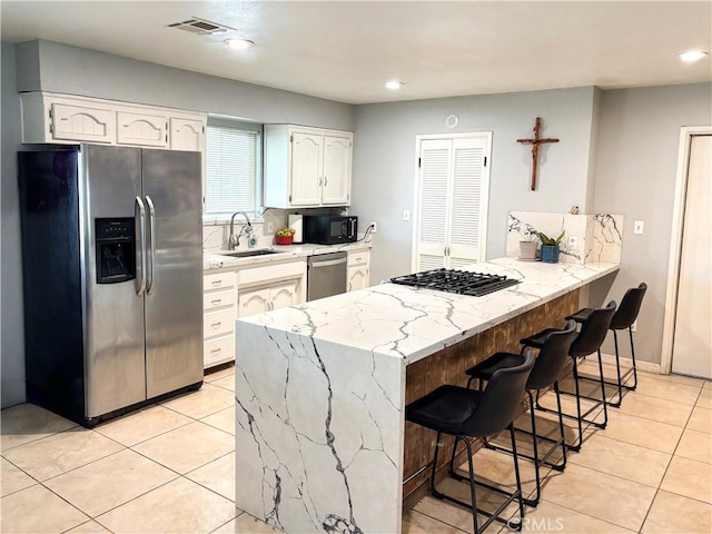 644 Whittendale St, Bakersfield, CA 93307 - kitchen with a peninsula, a sink, stainless steel appliances, white cabinetry, and visible vents
