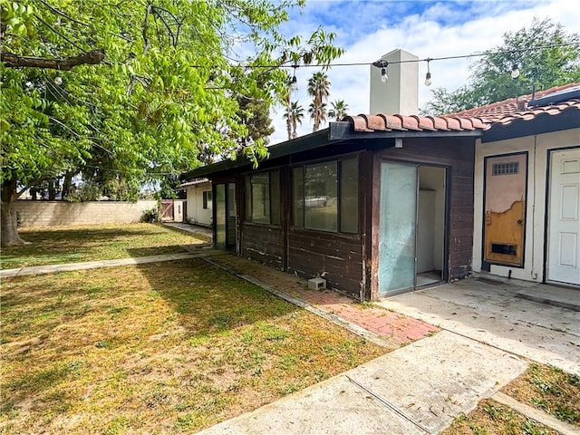644 Whittendale St, Bakersfield, CA 93307 - view of side of home featuring a tiled roof, fence, and a lawn