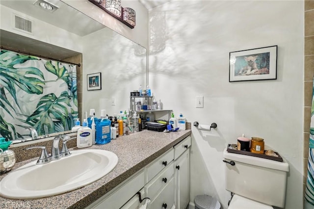bathroom featuring toilet, vanity, visible vents, and a shower with shower curtain