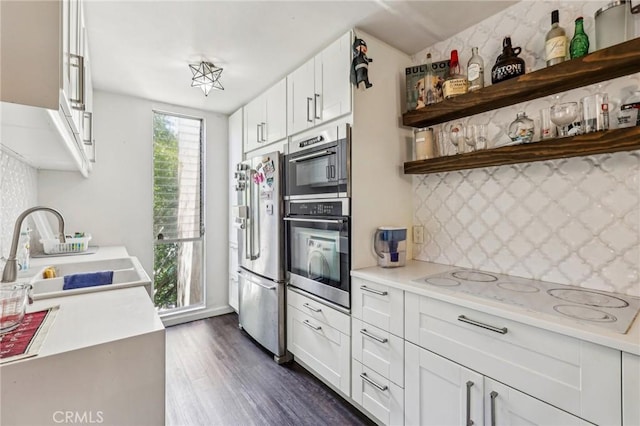 kitchen featuring a sink, light countertops, appliances with stainless steel finishes, tasteful backsplash, and dark wood-style floors