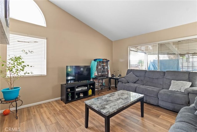living room with plenty of natural light, wood finished floors, baseboards, and high vaulted ceiling