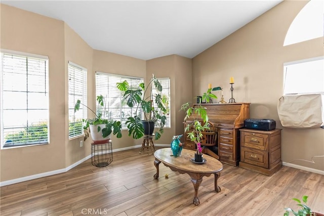 living area featuring light wood-style floors, vaulted ceiling, and baseboards