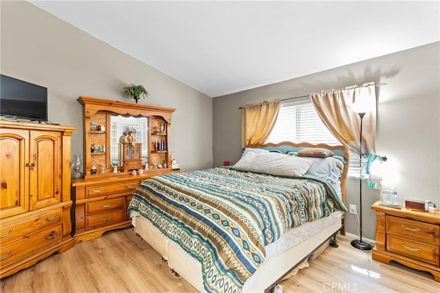 bedroom featuring light wood finished floors and lofted ceiling
