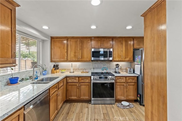 kitchen featuring a sink, stainless steel appliances, light wood-style floors, and brown cabinets