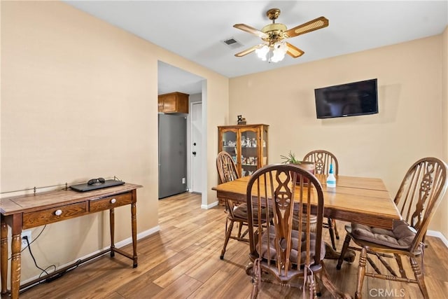 dining room featuring a ceiling fan, baseboards, light wood finished floors, and visible vents