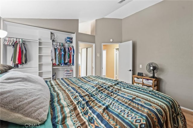 bedroom featuring vaulted ceiling, a closet, baseboards, and wood finished floors