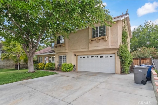 view of front of home featuring driveway, fence, an attached garage, stucco siding, and a front yard