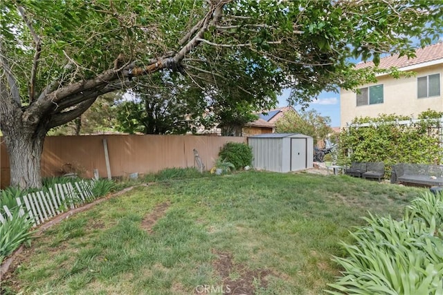 view of yard featuring a storage unit, a fenced backyard, and an outbuilding