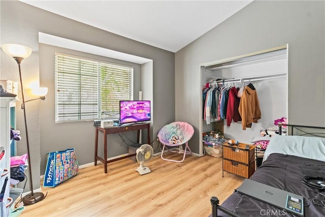 bedroom with baseboards, vaulted ceiling, a closet, and wood finished floors