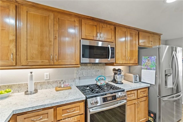 kitchen featuring brown cabinets, light stone countertops, and appliances with stainless steel finishes