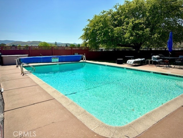 community pool featuring a hot tub, fence, and a patio
