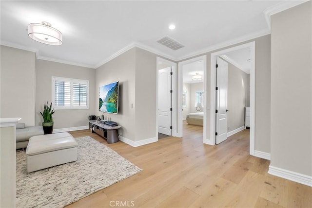 living area with baseboards, light wood-style floors, ornamental molding, and visible vents