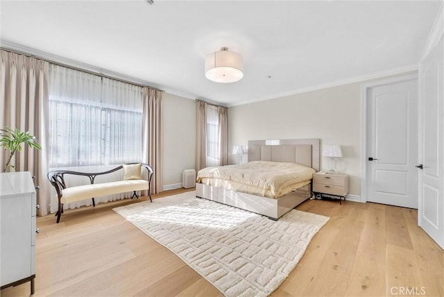 bedroom featuring light wood-type flooring, baseboards, and ornamental molding