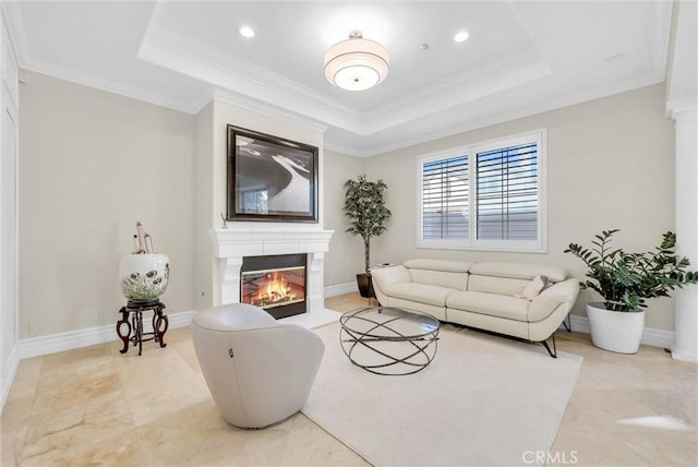 living room featuring crown molding, a raised ceiling, and a glass covered fireplace
