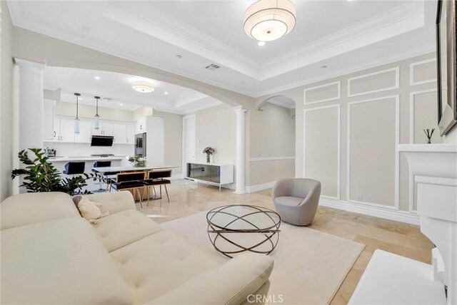 living room featuring visible vents, a tray ceiling, crown molding, and ornate columns