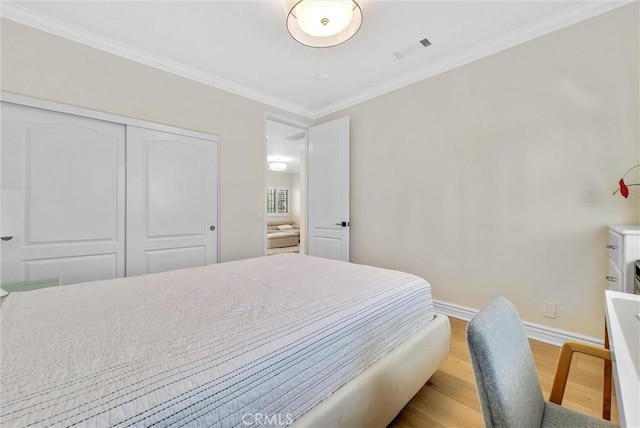 bedroom featuring a closet, wood finished floors, visible vents, crown molding, and baseboards