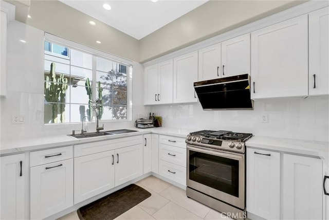 kitchen featuring a wealth of natural light, stainless steel gas range oven, range hood, and a sink