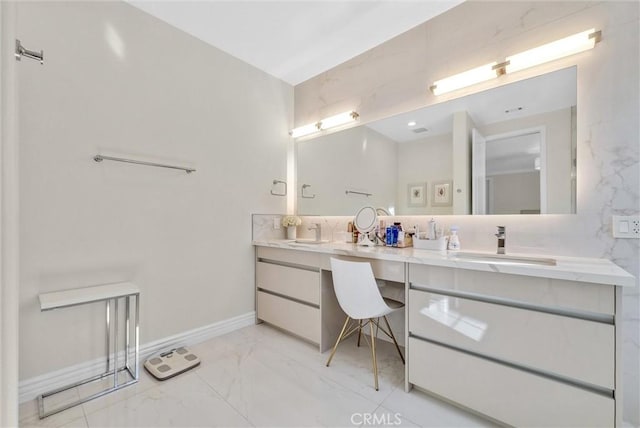 full bath with double vanity, marble finish floor, baseboards, and a sink