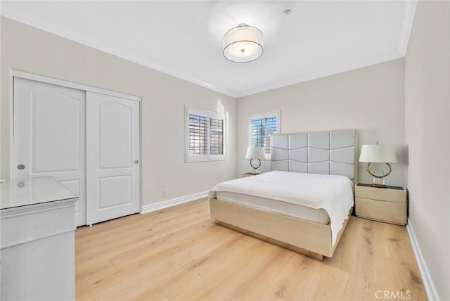 bedroom featuring crown molding, light wood-type flooring, a closet, and baseboards