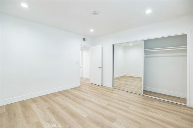 unfurnished bedroom featuring light wood finished floors, a closet, visible vents, and recessed lighting