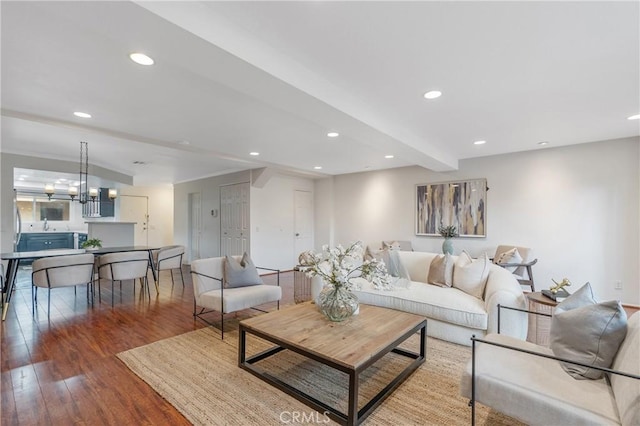 living area featuring a chandelier, recessed lighting, beam ceiling, and wood finished floors