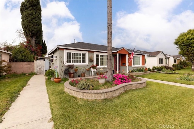 view of front of property with stucco siding, a front lawn, fence, and a gate