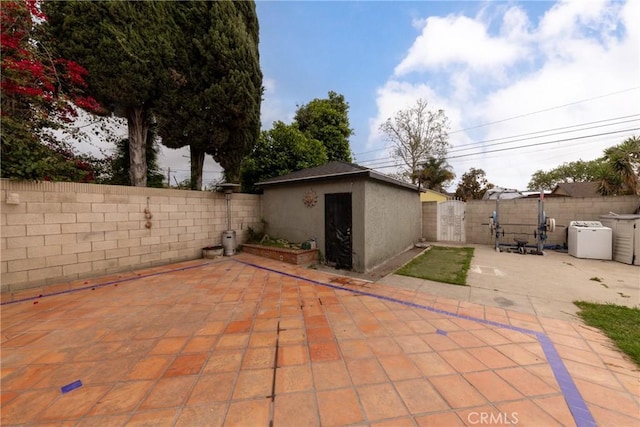 view of patio / terrace featuring a fenced backyard, a storage unit, and an outbuilding
