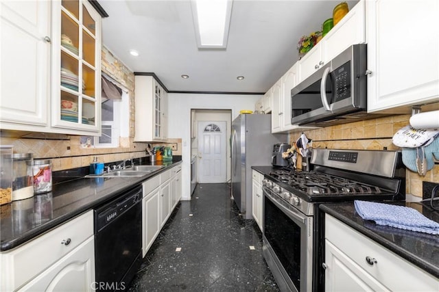 kitchen featuring glass insert cabinets, a sink, dark countertops, white cabinets, and appliances with stainless steel finishes