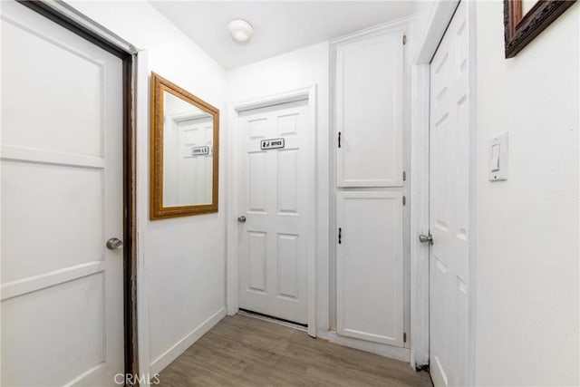 hall featuring light wood-style flooring and baseboards