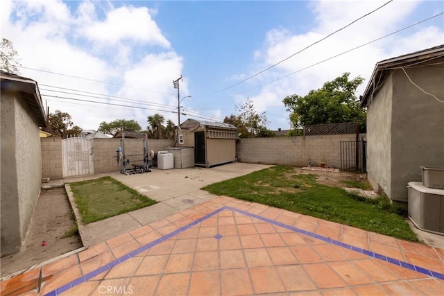 view of patio / terrace featuring an outbuilding, a shed, a fenced backyard, and a gate