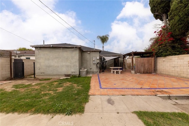 back of house featuring a gate, a gazebo, a patio area, fence, and stucco siding