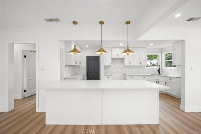 781 Sycamore Ct, Upland, CA 91786 - kitchen featuring tasteful backsplash, light wood-style flooring, white cabinets, a center island, and recessed lighting