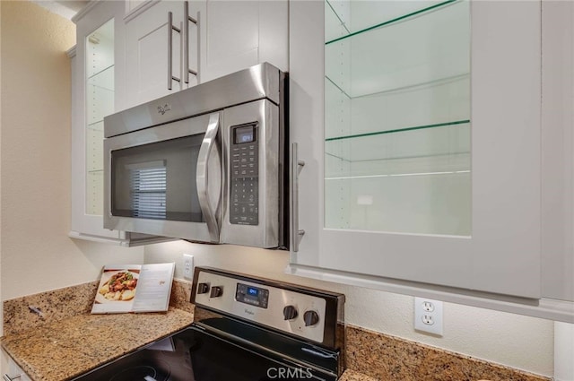 interior details featuring light stone countertops, white cabinets, and appliances with stainless steel finishes