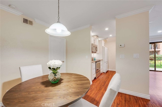 dining area featuring light wood-style flooring, recessed lighting, baseboards, visible vents, and crown molding