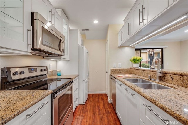 kitchen featuring a sink, white cabinetry, dark wood-type flooring, light stone countertops, and appliances with stainless steel finishes